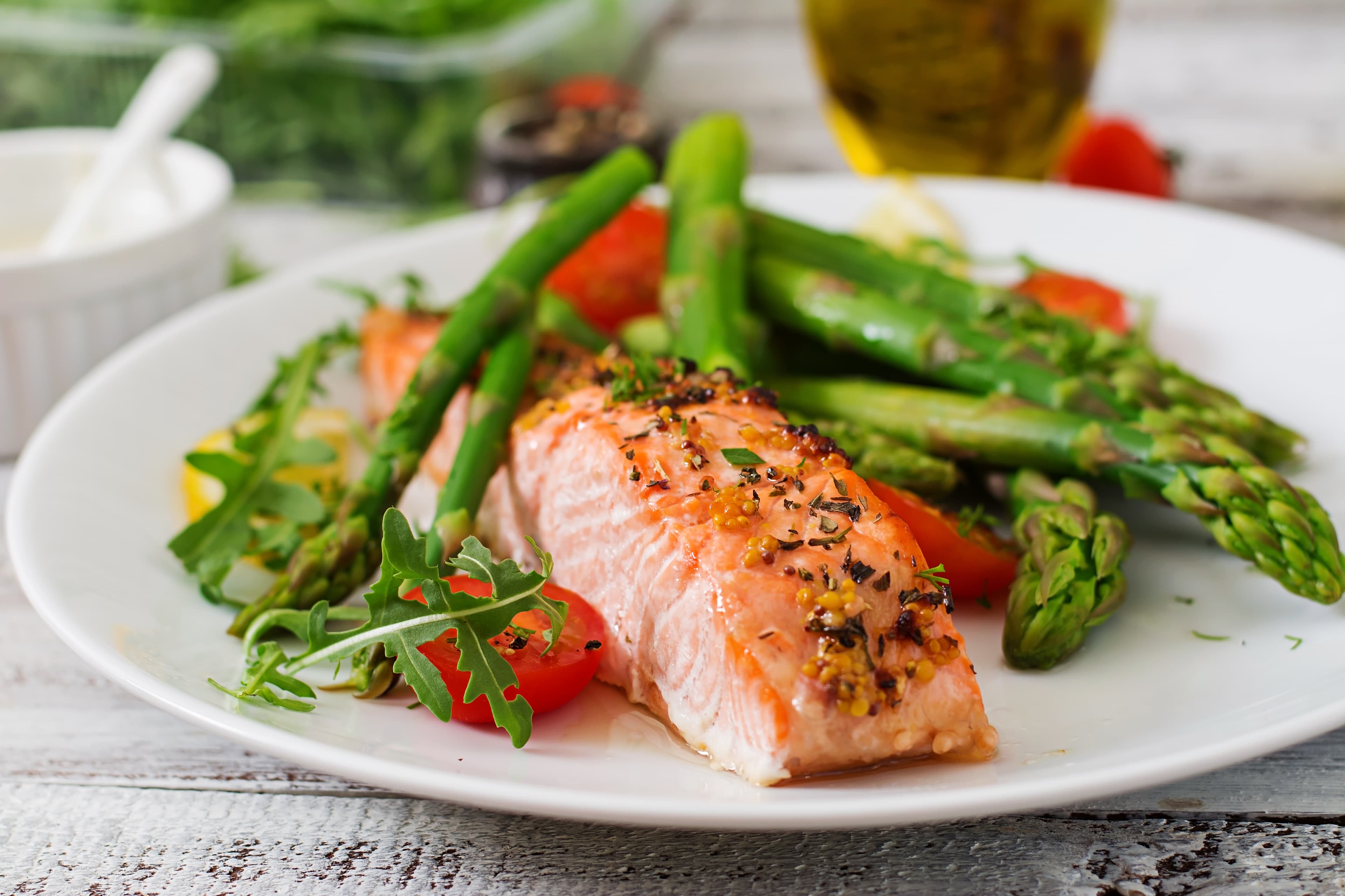 Baked salmon garnished with asparagus, tomatoes, and herbs